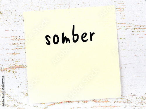 Obraz na plátně Yellow sticky note on wooden wall with handwritten word somber