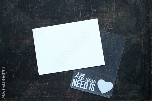 Biała kartka z miejscem na tekst i szablon "All you need is love" na ciemnym tle. Flat lay 