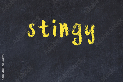 College chalk desk with the word stingy written on in photo