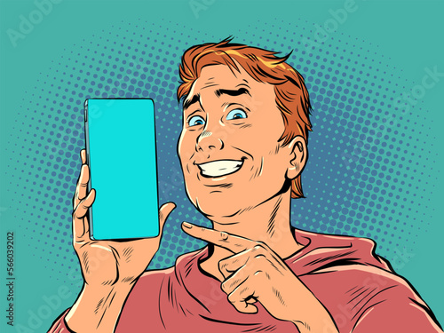 A man with red hair smiles and points to the phone. Product demonstration or offer on smartphone. The joy of a perfect purchase. Pop Art Retro