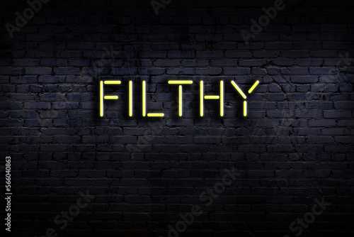 Fotografi Night view of neon sign on brick wall with inscription filthy