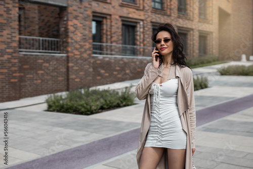stylish businesswoman in a raincoat in sunglasses talking on a mobile phone 