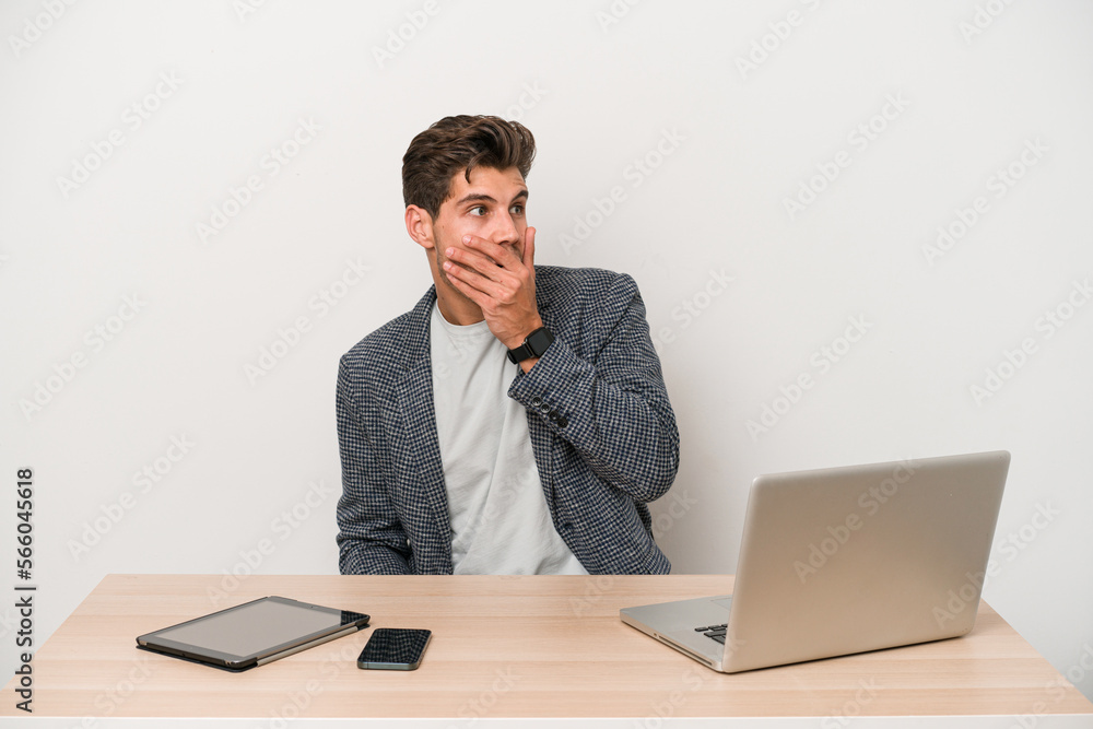 Young entrepreneur man working with a laptop isolated thoughtful looking to a copy space covering mouth with hand. Young entrepreneur man working with a laptop isolated thoughtful looking to a copy space covering mouth with hand.