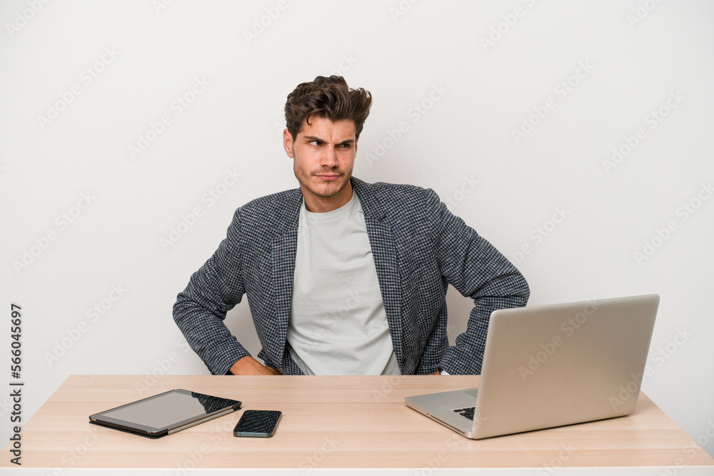 Young entrepreneur man working with a laptop isolated confused, feels doubtful and unsure. Young entrepreneur man working with a laptop isolated confused, feels doubtful and unsure.