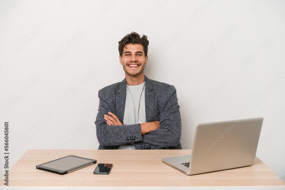 Young entrepreneur man working with a laptop isolated who feels confident, crossing arms with determination. Young entrepreneur man working with a laptop isolated who feels confident, crossing arms with determination.