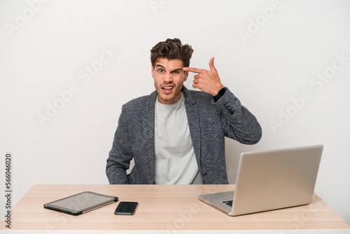 Young entrepreneur man working with a laptop isolated showing a disappointment gesture with forefinger.