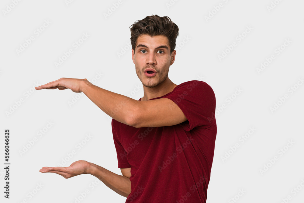 Young handsome caucasian man isolated on white background holding something with both hands, product presentation. Young handsome caucasian man isolated on white background holding something with both hands, product presentation.