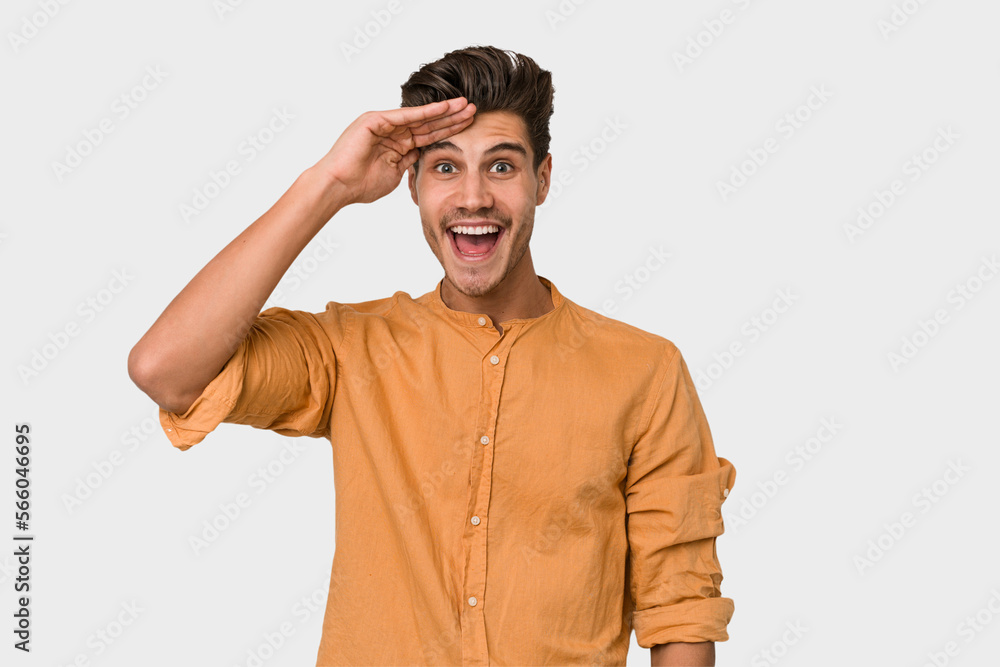 Young handsome caucasian man isolated on white background shouts loud, keeps eyes opened and hands tense.