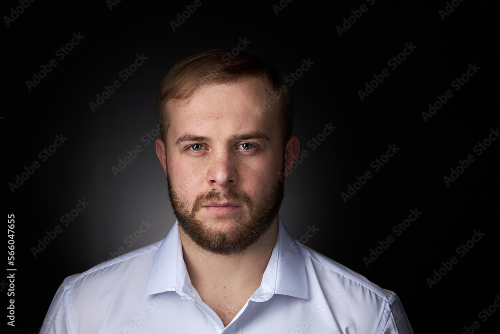 Young blond man with a beard, in a white shirt on a dark background. Young blond man with a beard, in a white shirt on a dark background.