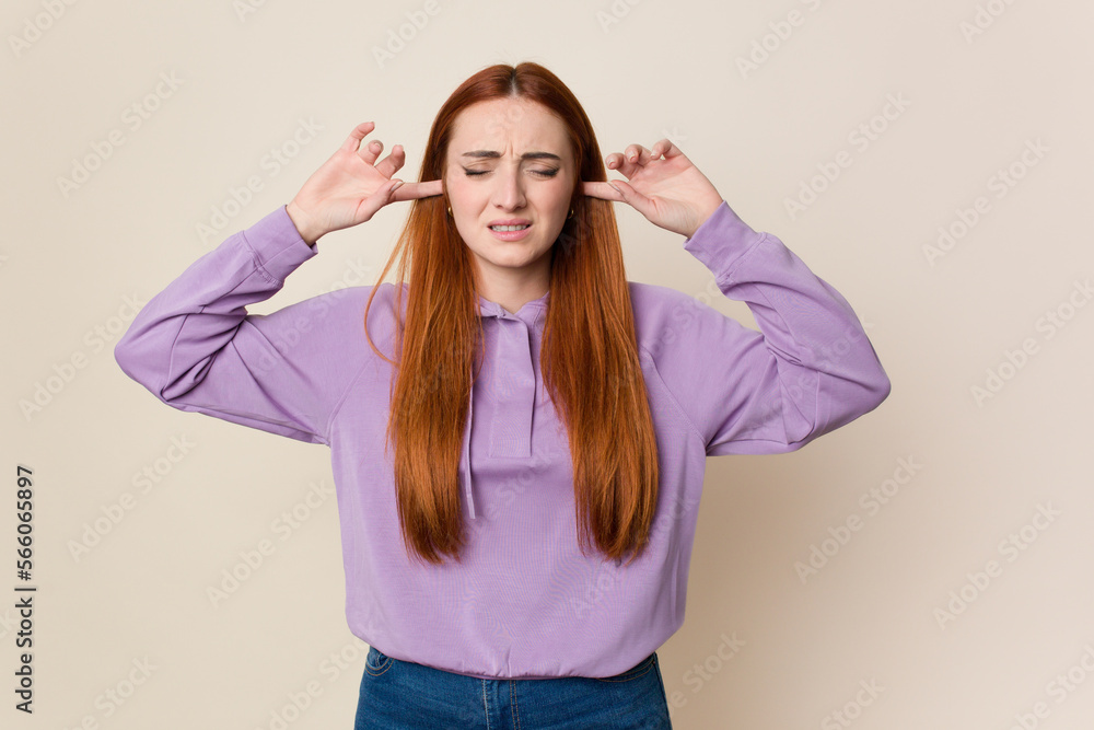 Young red hair woman isolated covering ears with fingers, stressed and desperate by a loudly ambient. Young red hair woman isolated covering ears with fingers, stressed and desperate by a loudly ambient.