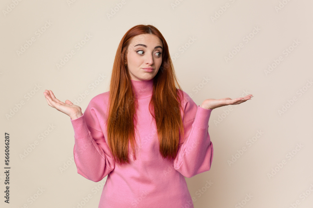 Young red hair woman isolated confused and doubtful shrugging shoulders to hold a copy space. Young red hair woman isolated confused and doubtful shrugging shoulders to hold a copy space.