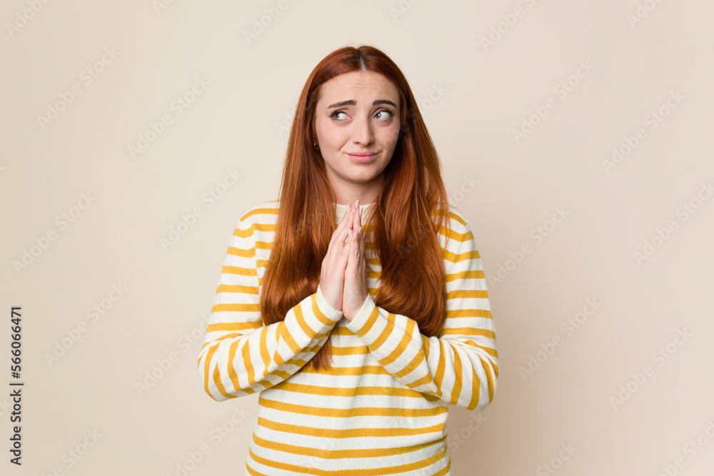 Young red hair woman isolated praying, showing devotion, religious person looking for divine inspiration. Young red hair woman isolated praying, showing devotion, religious person looking for divine inspiration.