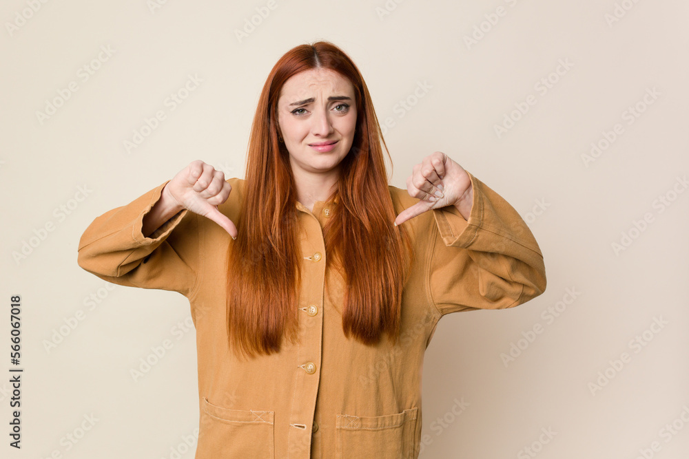 Young red hair woman isolated showing thumb down, disappointment concept. Young red hair woman isolated showing thumb down, disappointment concept.