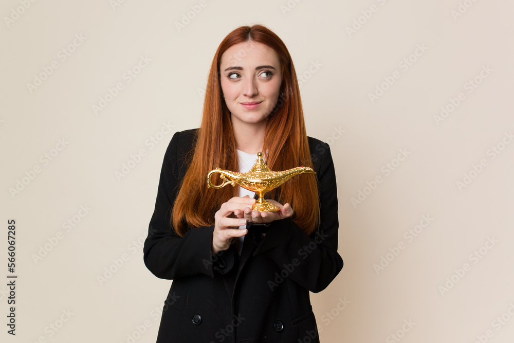 Young red hair business woman holding an arabic lamp making a wish Young red hair business woman holding an arabic lamp making a wish