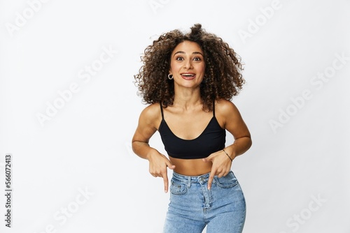Beautiful woman with curly afro hair posing on a white isolated background smile happiness in jeans and black top emotion, hand signs, copy space