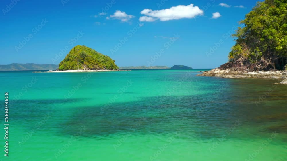 Aerial drone flight flying over a clear tropical ocean towards a bright, sunlit, sandy beach Aerial drone flight flying over a clear tropical ocean towards a bright, sunlit, sandy beach