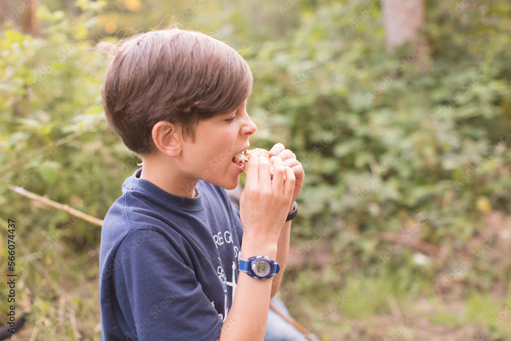 Side view of boy eating smore while standing on field Side view of boy eating smore while standing on field