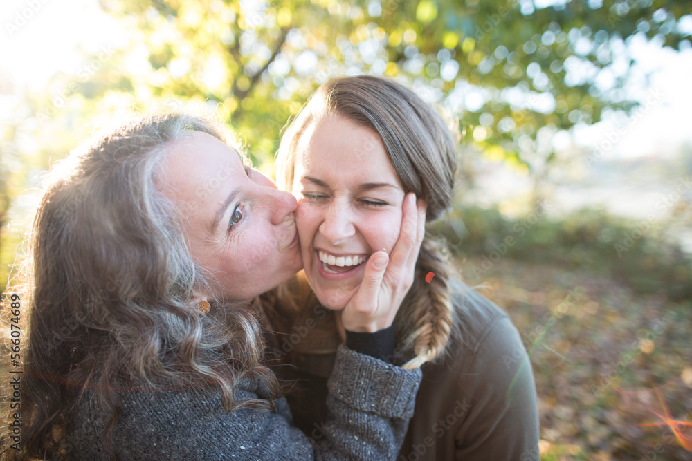 Woman giving friend kiss on cheek in park Woman giving friend kiss on cheek in park