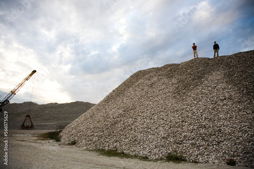 Two men stand atop a pile of oyster shells in Apalachicola, FL.