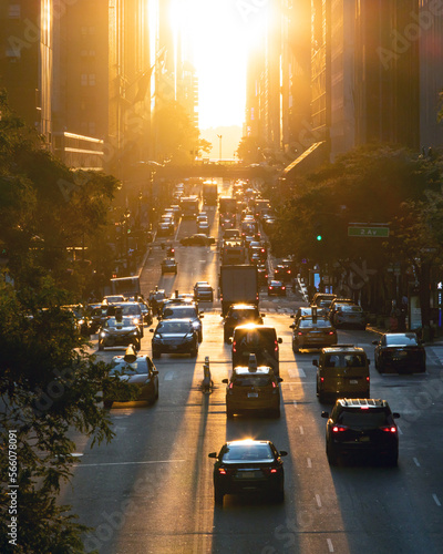 View of evening rush hour traffic traveling crosstown on 42nd Street through Manhattan New York City with sunlight shining between background buildings