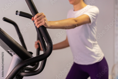 Young sportswoman exercising on elliptical cross trainer