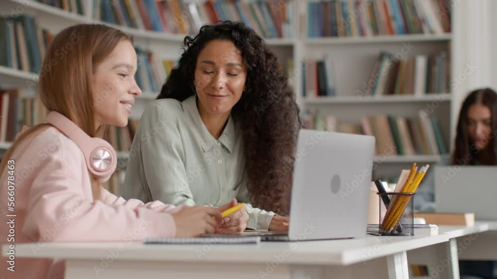 Group project. Two young happy women groupmates discussing lesson and doing homework on laptop together Group project. Two young happy women groupmates discussing lesson and doing homework on laptop together