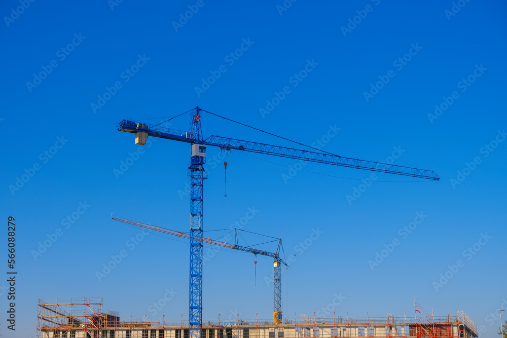 Building concept. Construction cranes.Construction machinery and building under construction on blue sky background.New house construction.