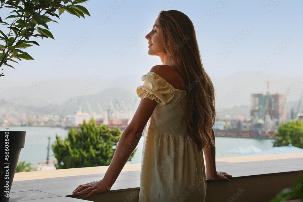 Beautiful young woman with long hair standing on balcony