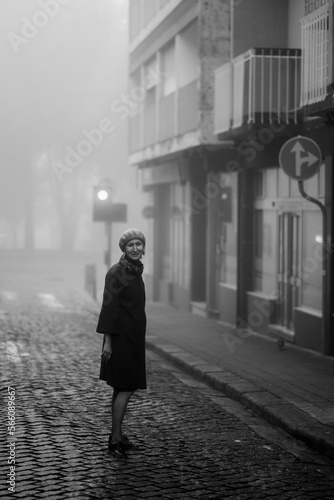 Obraz na płótnie A woman on the sidewalk in the thick fall morning fog. Black and white photo. w salonie