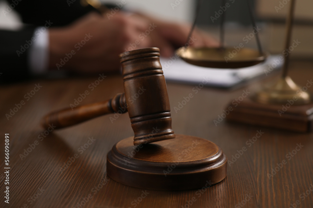 Law and justice. Closeup of judge working at wooden table, focus on gavel Law and justice. Closeup of judge working at wooden table, focus on gavel