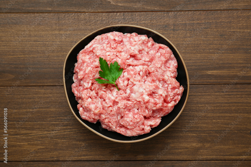 Bowl of raw fresh minced meat with parsley on wooden table, top view Bowl of raw fresh minced meat with parsley on wooden table, top view