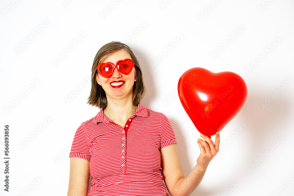 Beautiful smiling woman in red sunglasses holding in her hand a red heart balloon for Valentines Day. Beautiful smiling woman in red sunglasses holding in her hand a red heart balloon for Valentines Day.