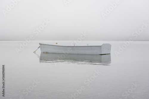 A dinghy floating in the ocean near shore on a foggy day.