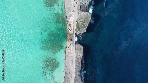 Cinematic aerial view descending top down drone shot of cars crossing glass window bridge on the island of eleuthera in the bahamas - separating the atlantic ocean from the caribbean sea
