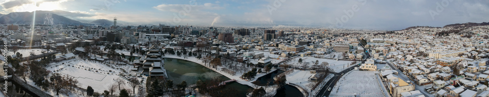 航空撮影した冬の松本城と松本市のパノラマの雪景色