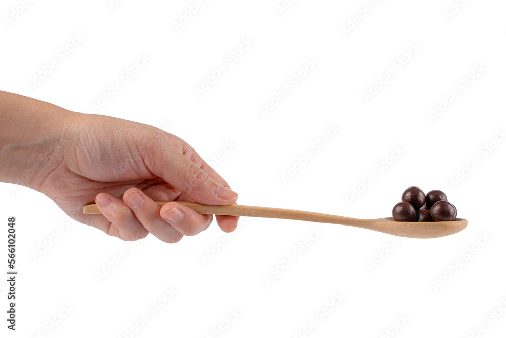 Hand holding wooden spoon on chocolate balls on white background.