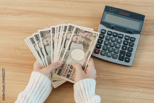 Woman hand counting Japanese Yen banknote with calculator Fototapet