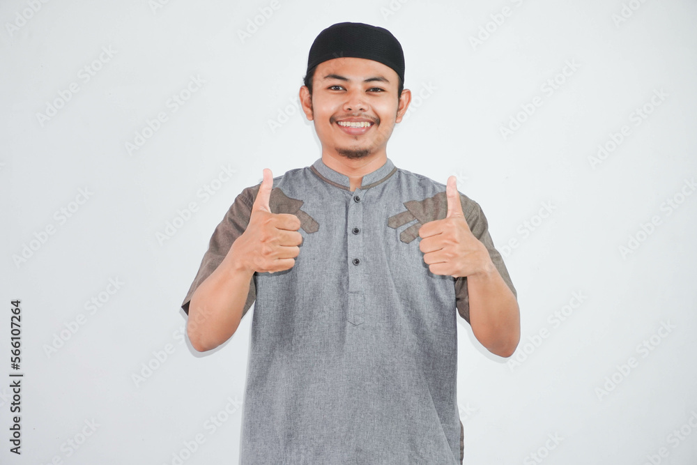 smiling or happy young muslim man showing hand thumbs up wearing grey muslim clothes isolated on white background smiling or happy young muslim man showing hand thumbs up wearing grey muslim clothes isolated on white background