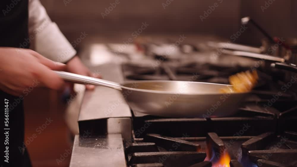 Cook shakes the silver pan with pasta back and forth while the pasta cooks on the fire. Close up dolley shot Cook shakes the silver pan with pasta back and forth while the pasta cooks on the fire. Close up dolley shot
