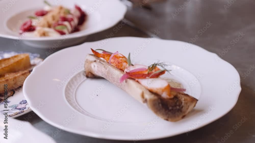 Close-up panning shot of a beautifully decorated dinner plate with a course prepared on a bone Close-up panning shot of a beautifully decorated dinner plate with a course prepared on a bone