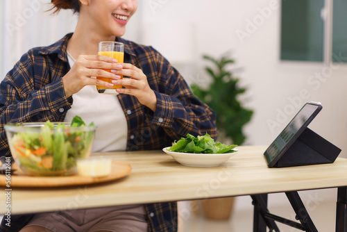 Lifestyle in living room concept  Asian woman watching movie on tablet and drinking orange juice