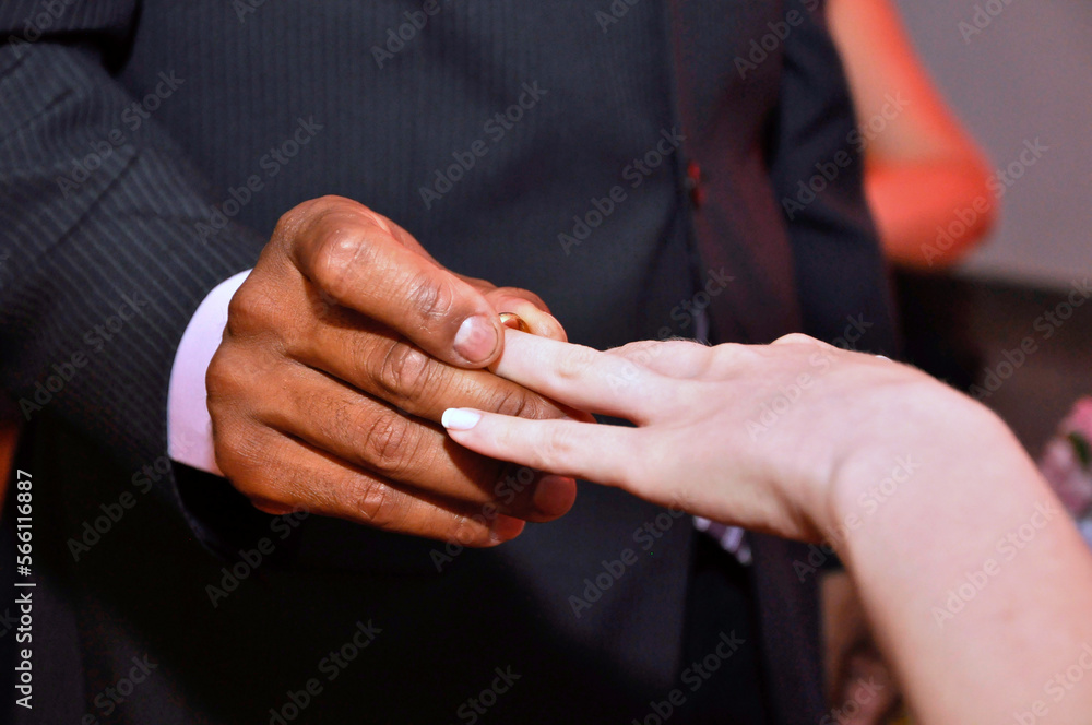 Groom puts wedding ring on bride's finger at wedding ceremony.