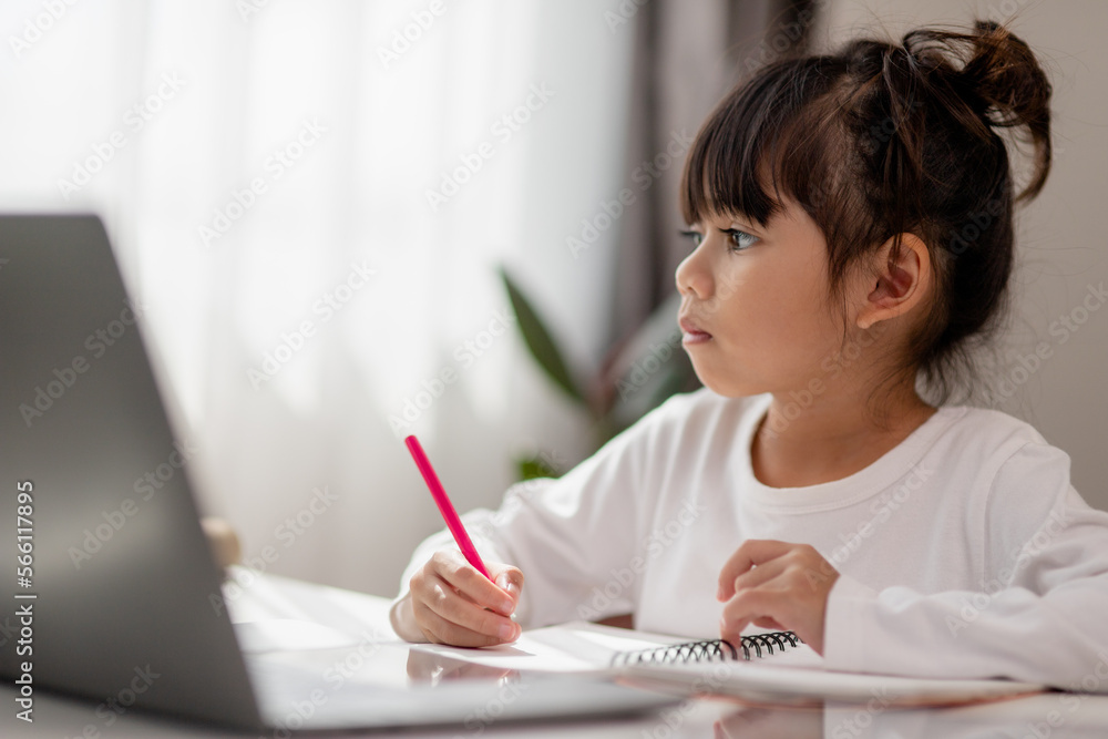 Asian schoolgirl doing her homework with laptop at home. Children use gadgets to study. Education and distance learning for kids. Homeschooling during quarantine. Stay at home Asian schoolgirl doing her homework with laptop at home. Children use gadgets to study. Education and distance learning for kids. Homeschooling during quarantine. Stay at home
