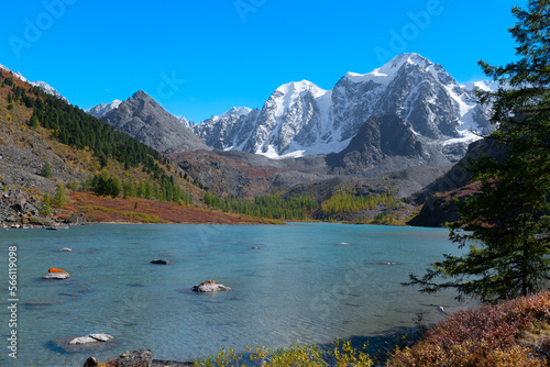 Snowy mountain peaks with rocks with glaciers near the alpine transparent lake Shavlinskoye in Altai during the day. Peaks Dream, Fairy Tale, Beauty. photo