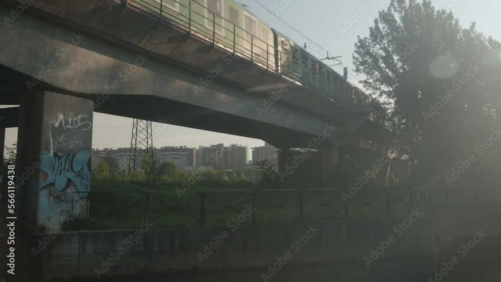 Subway ride on concrete bridge in Milan, view from bellow. Lens flare