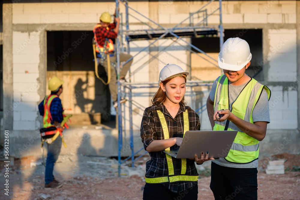 Male construction engineer talking to two female architects. using a notebook computer standing at the construction site to explain home design work Male construction engineer talking to two female architects. using a notebook computer standing at the construction site to explain home design work