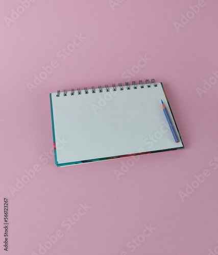 Spiral notebook with blue pencil on pink background. Clean sheet for text. © Vin.rusanov