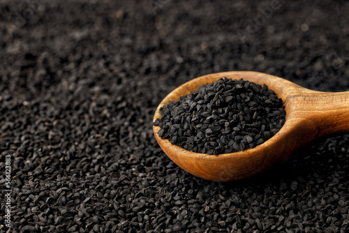 black cumin seeds in scoop and scattered on background