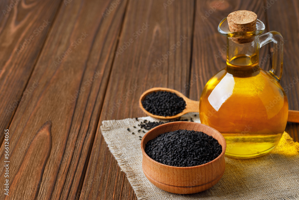 black cumin oil in glass bottle and seeds in bowl and in spoon on table black cumin oil in glass bottle and seeds in bowl and in spoon on table