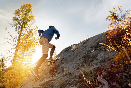 Runner man runs uphill crosscountry in sunset forest and mountains photo